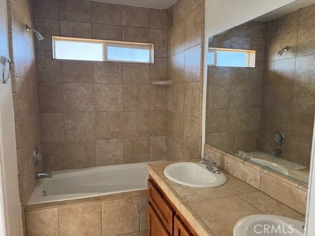 a bathroom with a granite countertop sink mirror toilet and bathtub