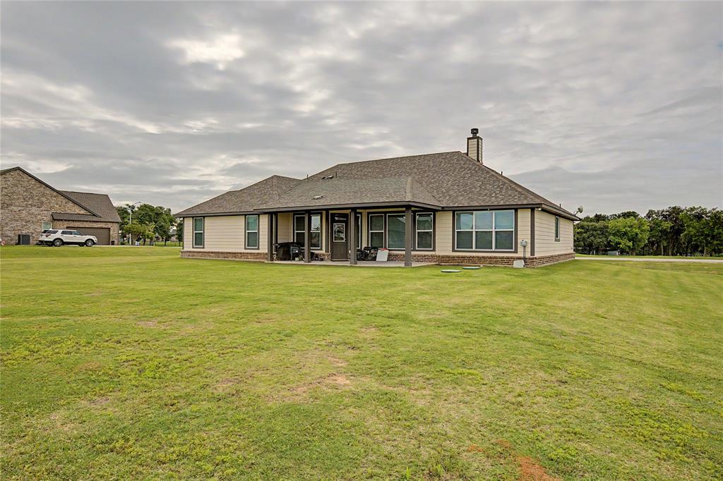 185 Chester Road Springtown, TX 76082 - Photo 35 of 40 Expansive green lawn surrounds a single-story residence with a covered patio