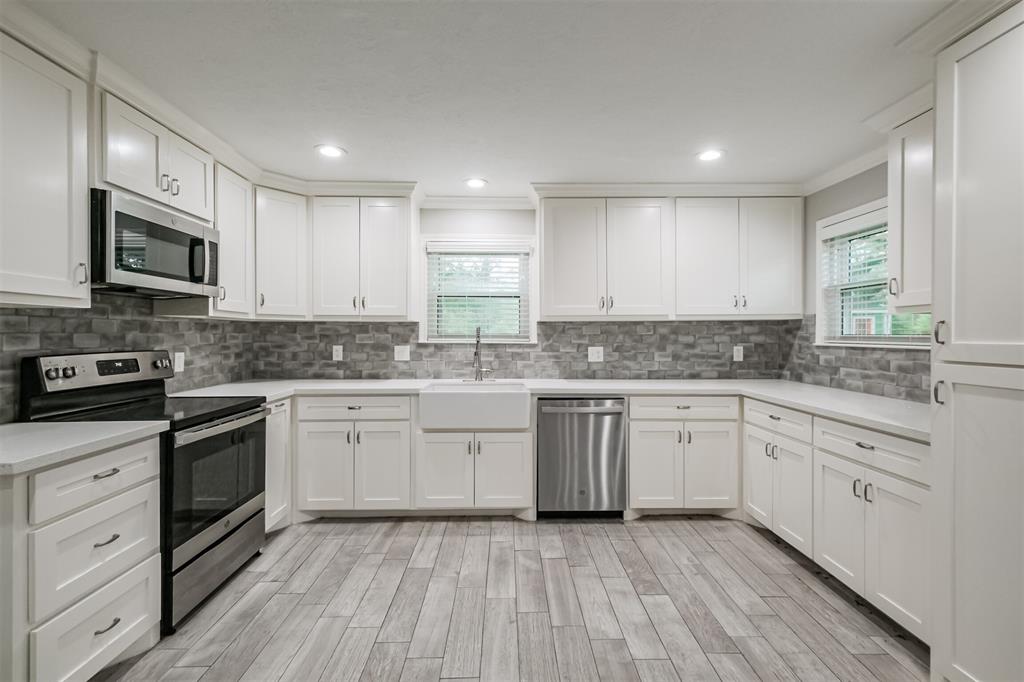 a kitchen with granite countertop white cabinets stainless steel appliances a sink and a stove