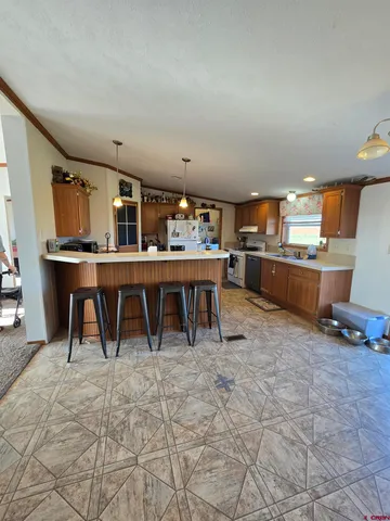 a room with stainless steel appliances lots of wooden furniture a rug and a chair