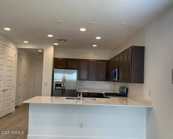 a large kitchen with stainless steel appliances a large counter top a stove and a refrigerator with wooden floor