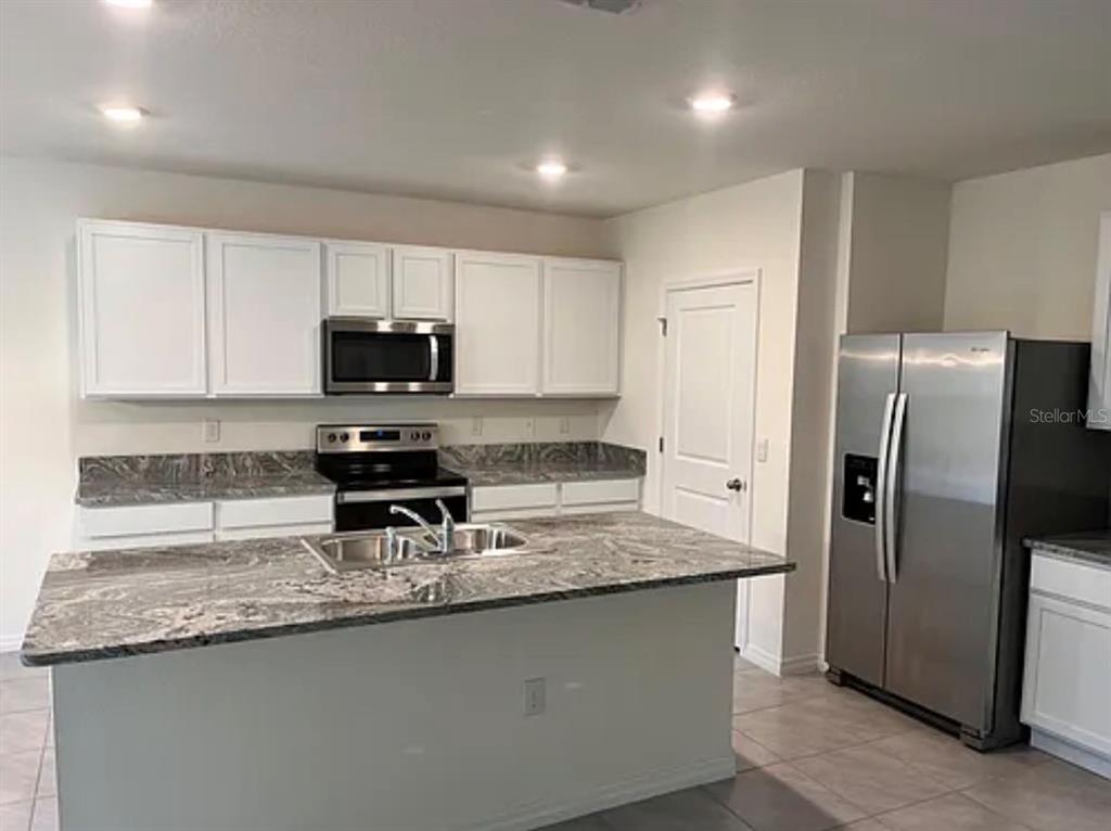 5 Hickory Course Loop Ocala, FL 34472 - Photo 3 of 10 a kitchen with granite countertop a refrigerator a sink a stove a microwave a counter top space and cabinets