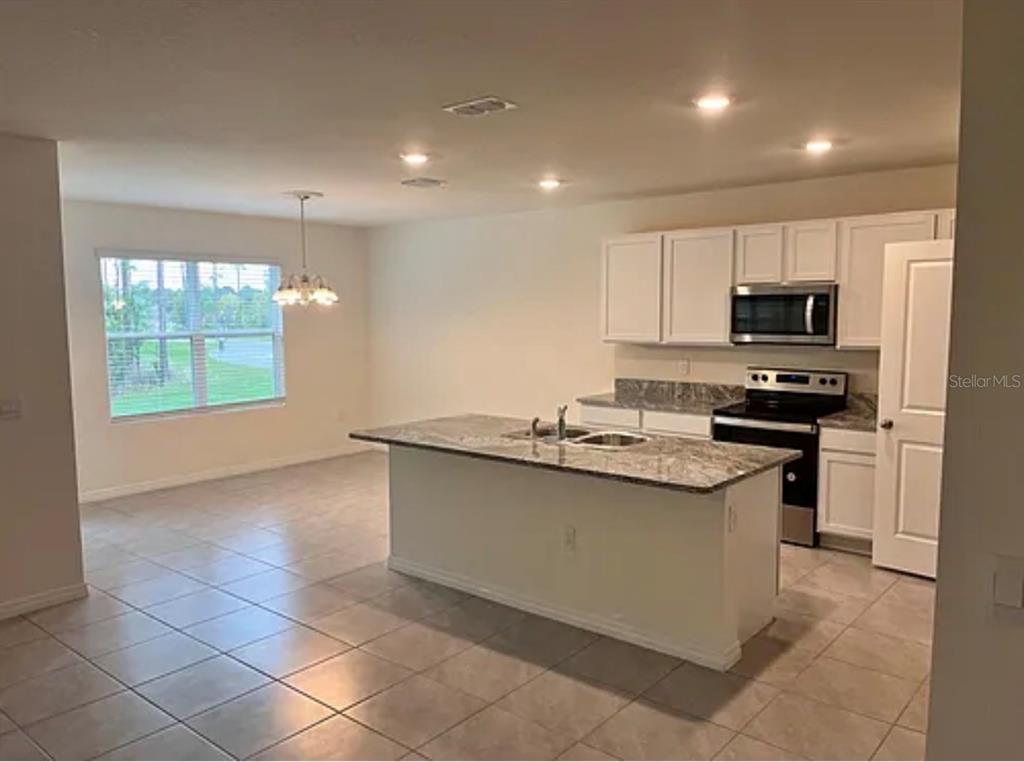 5 Hickory Course Loop Ocala, FL 34472 - Photo 5 of 10 a kitchen with kitchen island granite countertop a sink and a stove top oven with wooden floor
