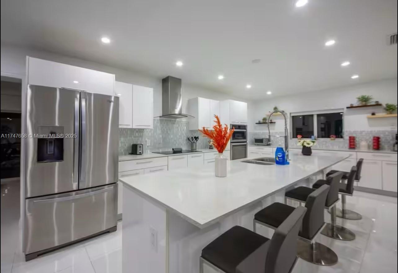 2271 Northeast 191st Street Miami, FL 33180 - Photo 13 of 24 a kitchen with stainless steel appliances a refrigerator and a stove top oven with white cabinets
