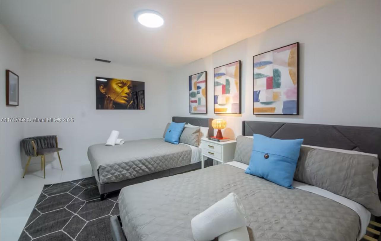 2271 Northeast 191st Street Miami, FL 33180 - Photo 18 of 24 a bedroom with two beds and painting on the wall
