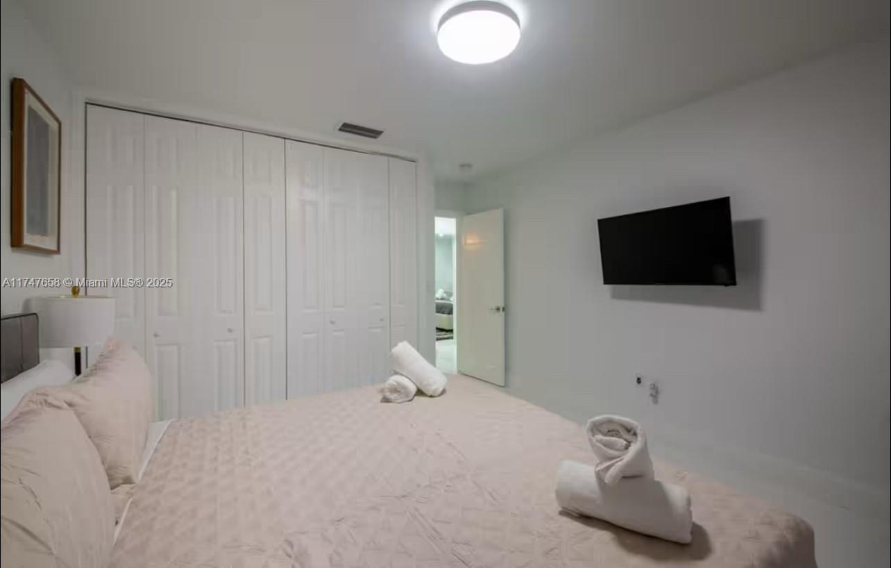 2271 Northeast 191st Street Miami, FL 33180 - Photo 19 of 24 a bedroom with a bed and a flat screen tv