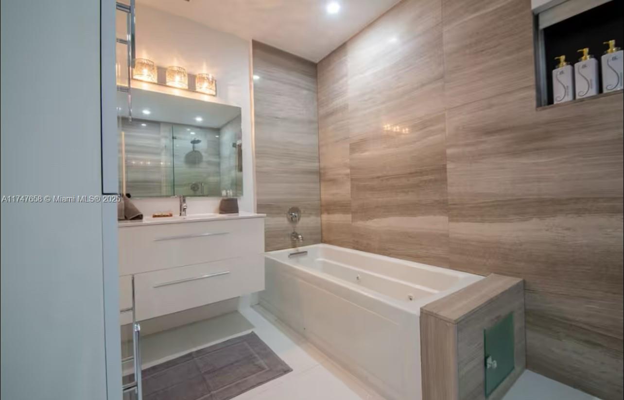 2271 Northeast 191st Street Miami, FL 33180 - Photo 21 of 24 a bathroom with a sink a mirror and a bathtub