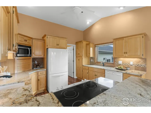 a kitchen with granite countertop a refrigerator stove top oven and sink