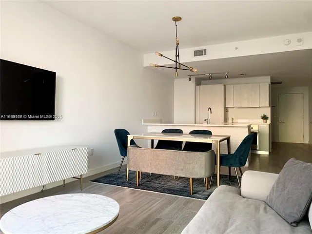a living room with a couch a flat screen tv and kitchen view