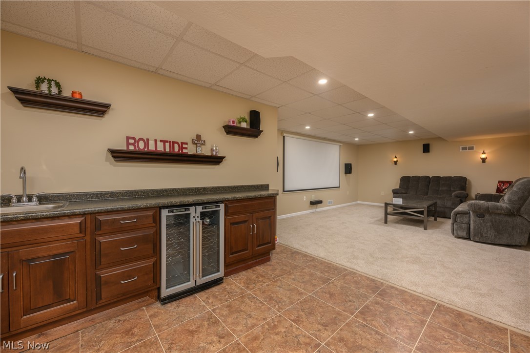 806 Forrest Ridge Drive Dover, OH 44622 - Photo 33 of 36 Indoor wet bar featuring open shelves, dark countertops, light colored carpet, a paneled ceiling, and wine cooler
