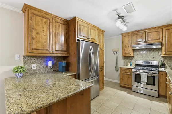 a kitchen with stainless steel appliances granite countertop a stove refrigerator and cabinets
