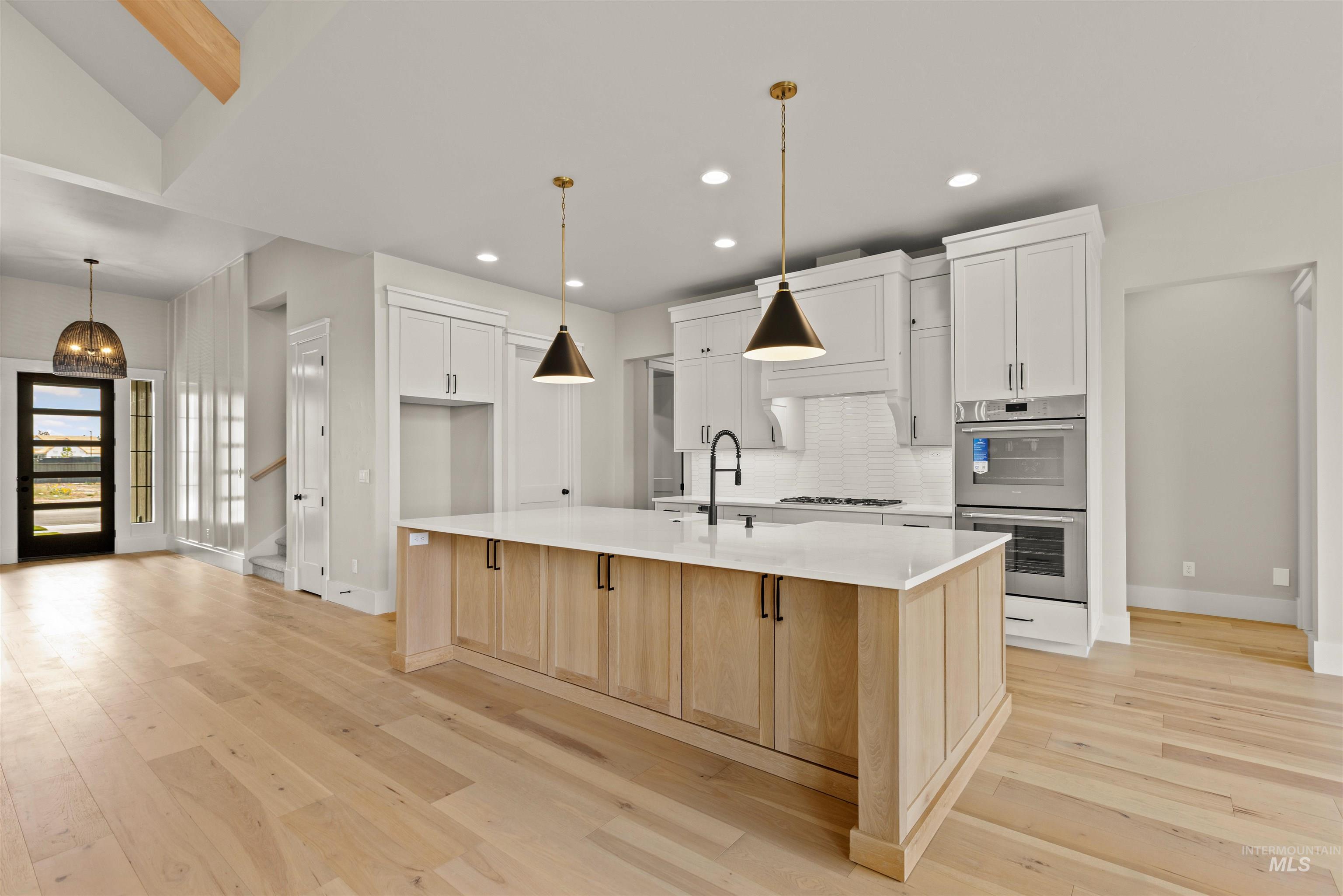 6891 South Utmost Way Meridian, ID 83642 - Photo 17 of 46 Kitchen with light brown cabinetry, stainless steel double oven, white cabinets, tasteful backsplash, and a large island with sink
