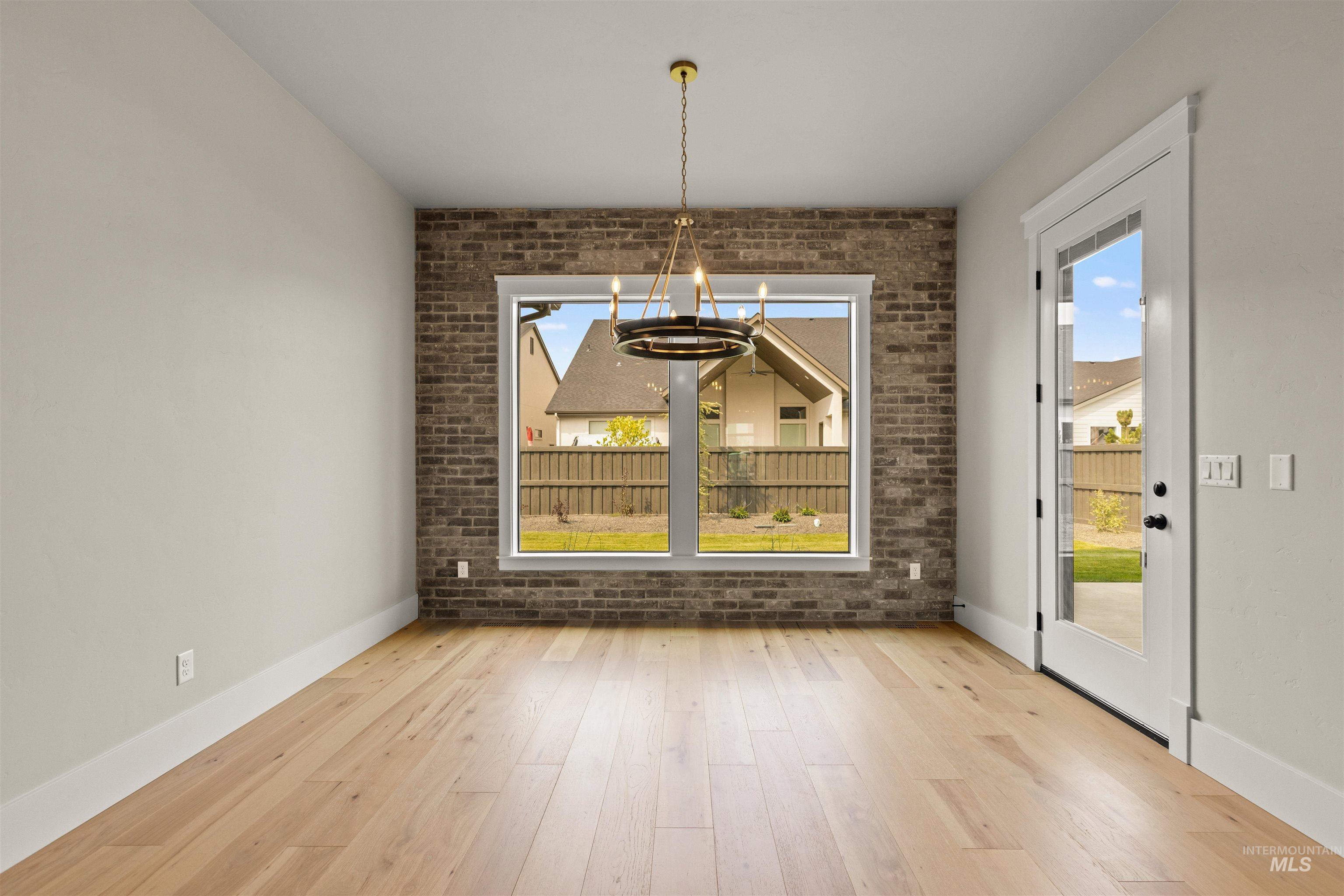 6891 South Utmost Way Meridian, ID 83642 - Photo 23 of 46 Unfurnished dining area featuring brick wall, a chandelier, and wood finished floors
