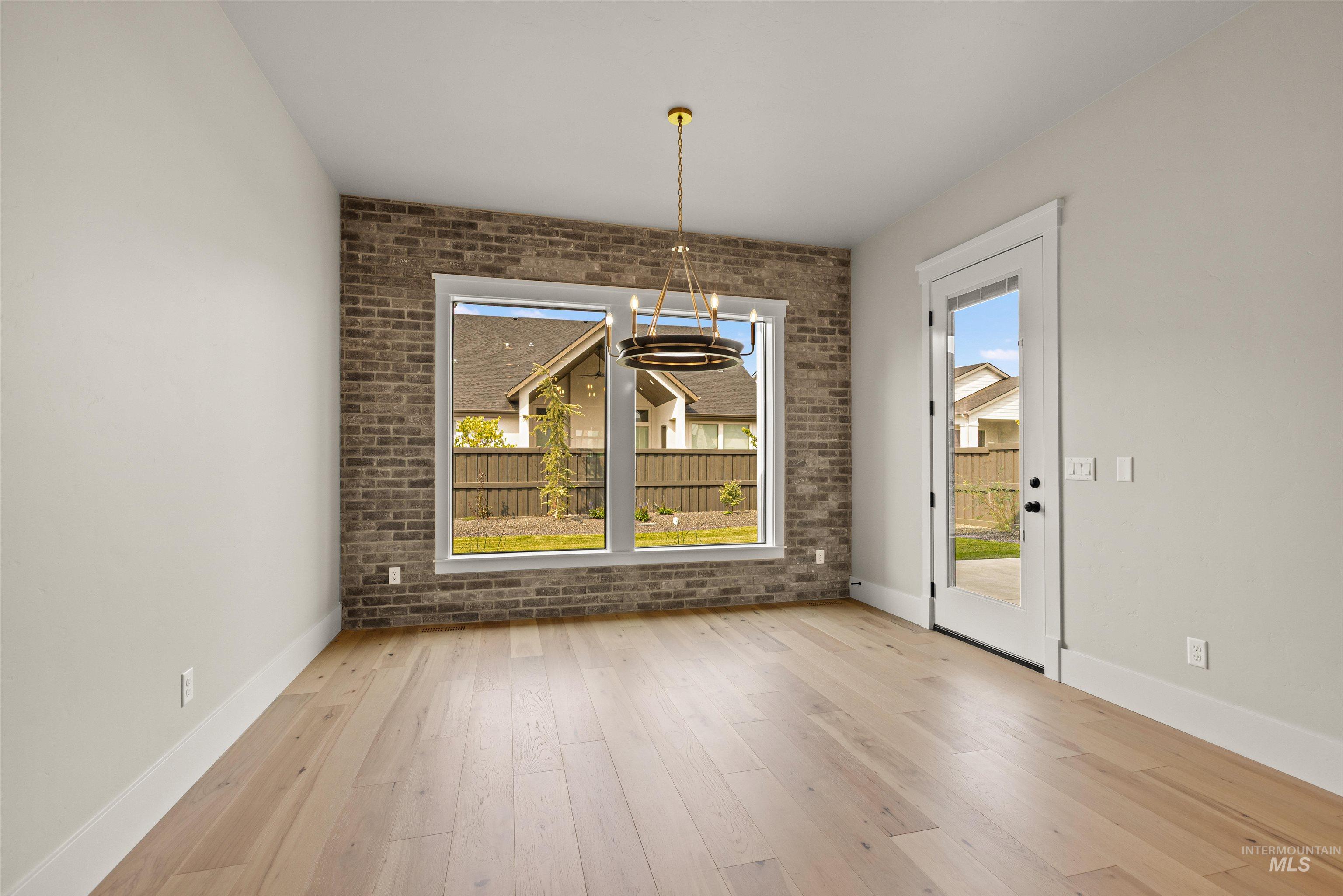 6891 South Utmost Way Meridian, ID 83642 - Photo 24 of 46 Unfurnished dining area featuring brick wall, light wood-type flooring, and a chandelier