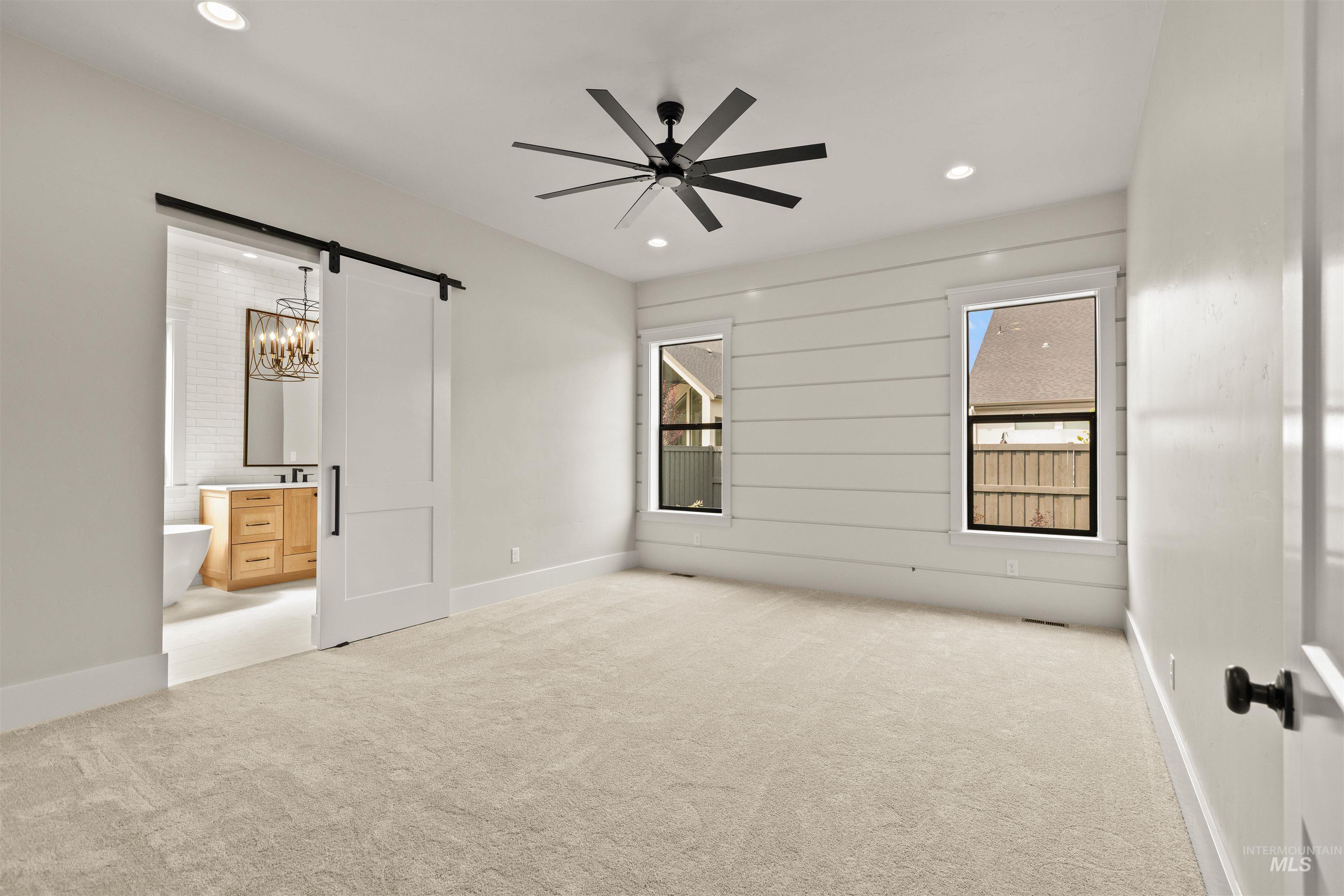 6891 South Utmost Way Meridian, ID 83642 - Photo 25 of 46 Unfurnished bedroom with a barn door, carpet, ceiling fan, recessed lighting, and connected bathroom
