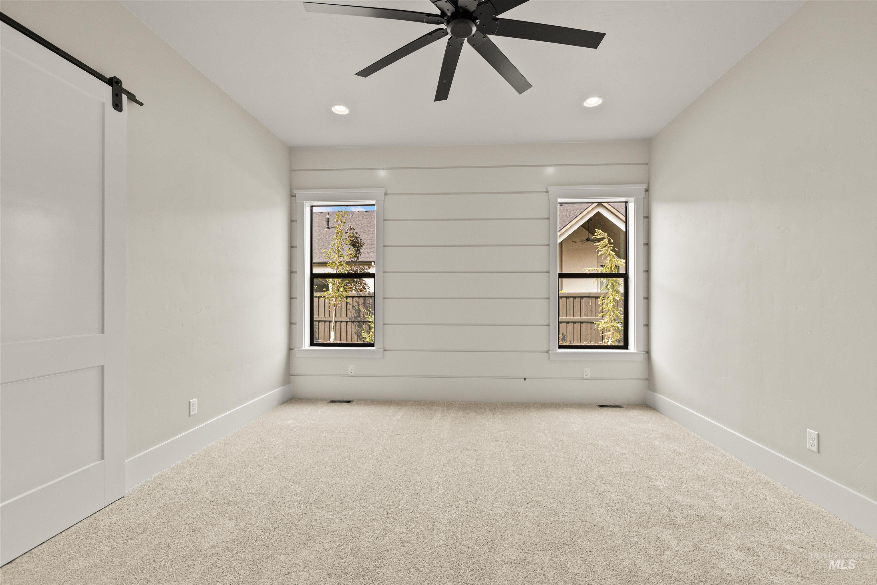 6891 South Utmost Way Meridian, ID 83642 - Photo 26 of 46 Empty room with a barn door, carpet flooring, recessed lighting, and a ceiling fan