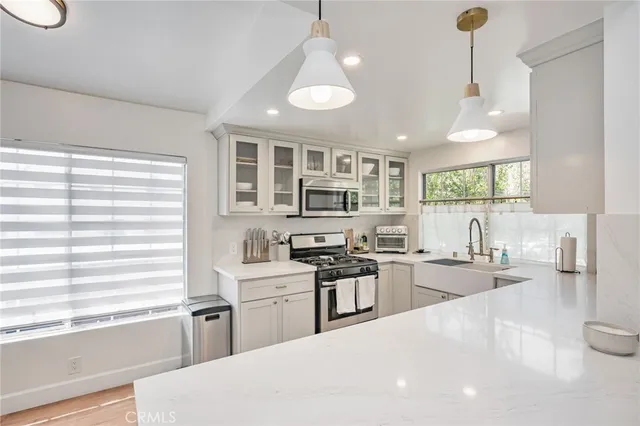 a kitchen with stainless steel appliances a refrigerator a sink a stove a dining table and chairs