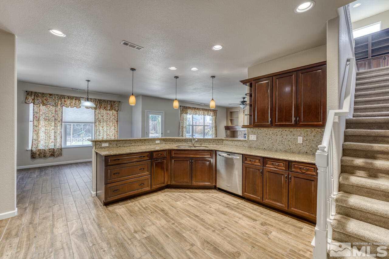 9720 Lemke Court Reno, NV 89521 - Photo 19 of 40 a large kitchen with kitchen island granite countertop wooden cabinets a sink and dishwasher