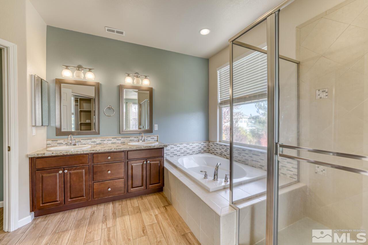 9720 Lemke Court Reno, NV 89521 - Photo 24 of 40 a bathroom with a granite countertop sink a mirror and a bathtub
