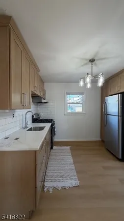 a large kitchen with a stove a sink dishwasher a kitchen island with wooden cabinets and floor