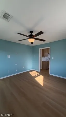 an empty room with wooden floor a ceiling fan and windows