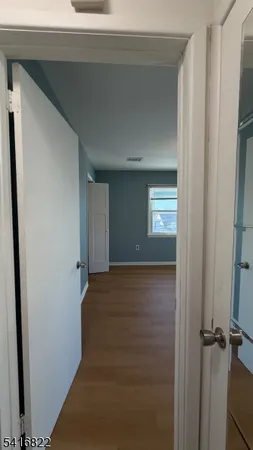 a view of an empty room with wooden floor and window
