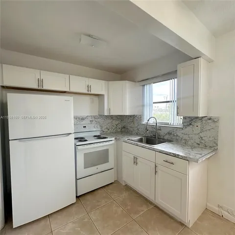 a kitchen with white cabinets sink and white appliances