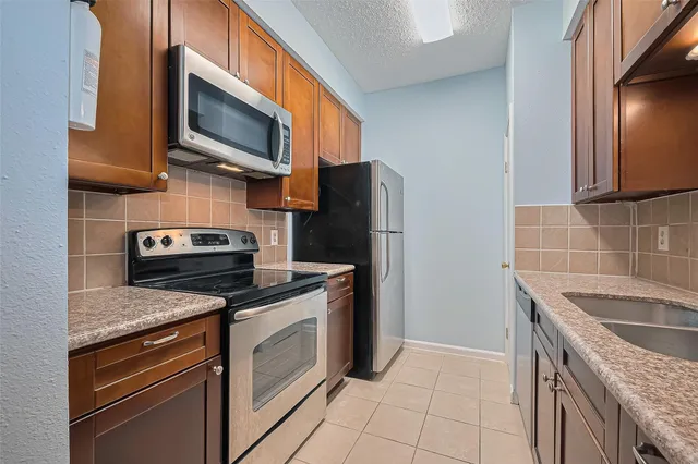 a kitchen with stainless steel appliances granite countertop a stove microwave refrigerator and sink