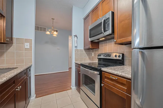 a kitchen with granite countertop wooden cabinets and stainless steel appliances