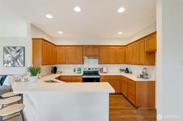 a kitchen with a stove a sink dishwasher and a refrigerator with wooden floor