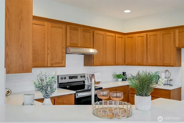a kitchen with stainless steel appliances granite countertop a refrigerator a stove a sink and white cabinets