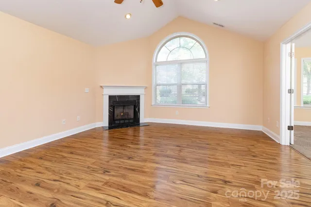 an empty room with wooden floor cabinet and a window