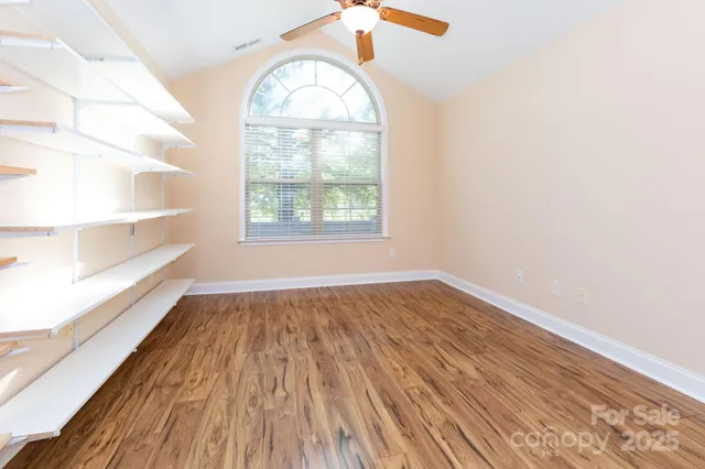an empty room with wooden floor cabinet and windows