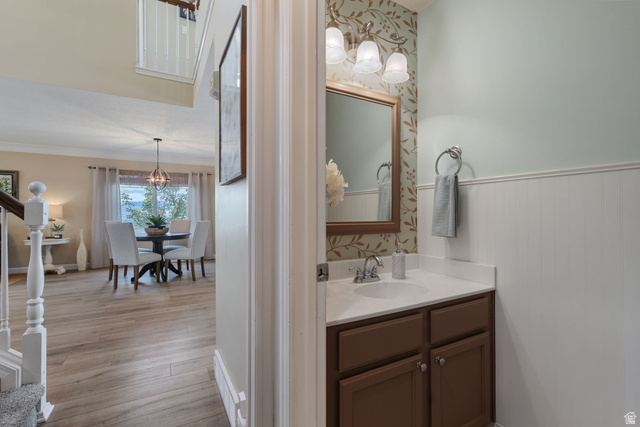 14883 Tooele Lane Draper, UT 84020 - Photo 21 of 49 Powder room featuring a brown vanity with a white countertop and undermount sink, beadboard paneling, and a framed mirror