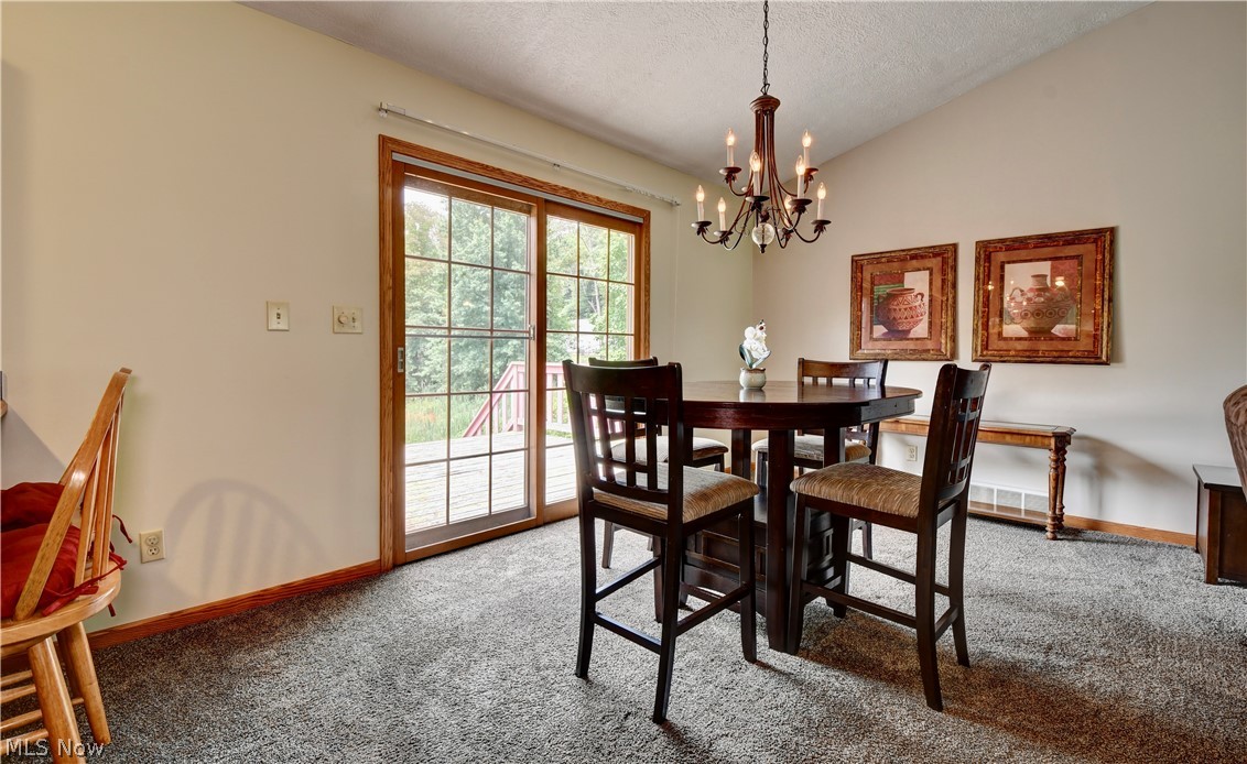 3318 Simpson Road Southeast Dennison, OH 44621 - Photo 14 of 31 Dining room featuring vaulted ceiling, a notable chandelier, carpet floors, and a textured ceiling
