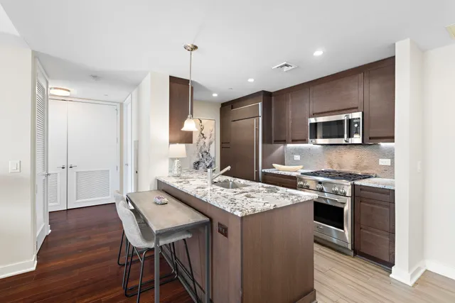 a kitchen with a stove a sink dishwasher a refrigerator with a dining table and chairs