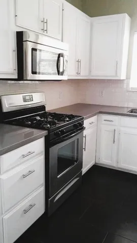 a kitchen with white cabinets and black appliances