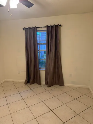 a view of an empty room and chandelier fan