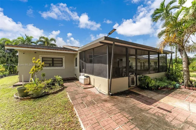 a view of a house with a big yard plants and large trees