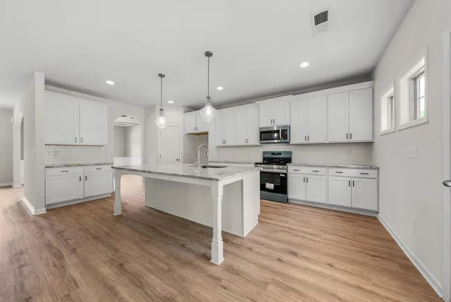 a large kitchen with cabinets wooden floor and stainless steel appliances