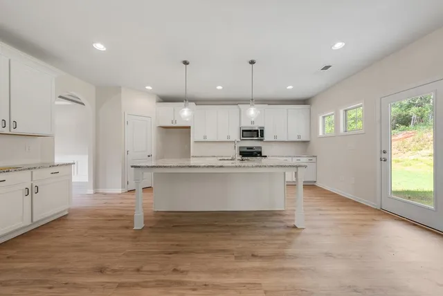 a view of kitchen with granite countertop stainless steel appliances refrigerator stove microwave and cabinets