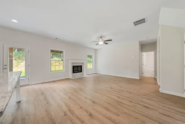 an empty room with wooden floor fireplace and windows