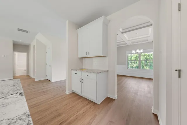 an empty room with wooden floor cabinet and windows