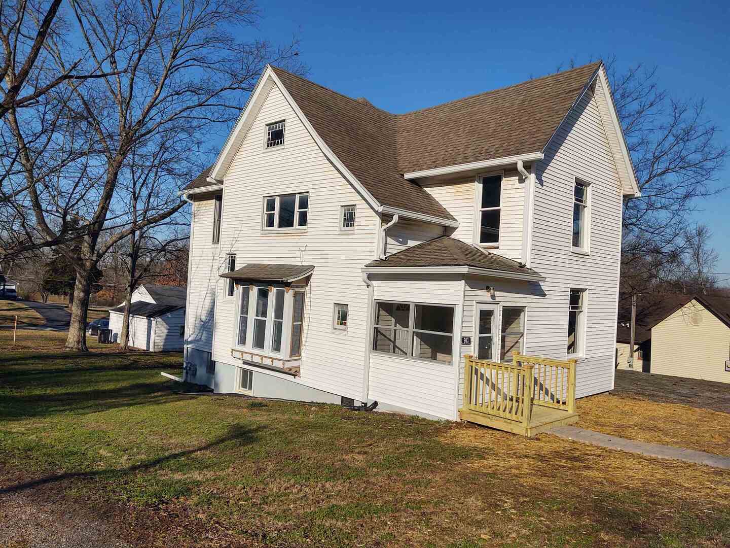 a view of a white house with large windows and a yard
