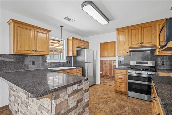 a kitchen with stainless steel appliances granite countertop a stove a sink and a refrigerator