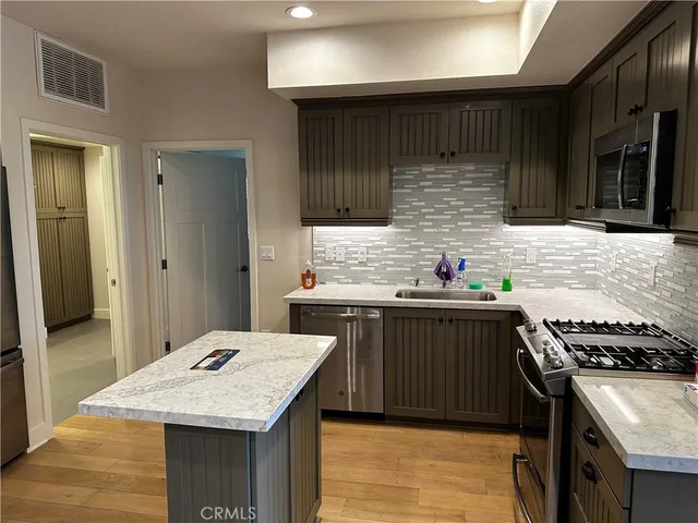 a kitchen with stainless steel appliances kitchen island granite countertop a stove and a sink