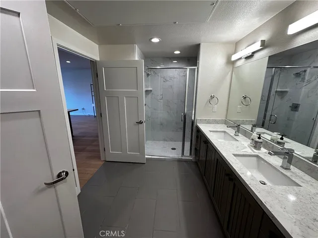 a bathroom with a double vanity sink a large mirror and shower