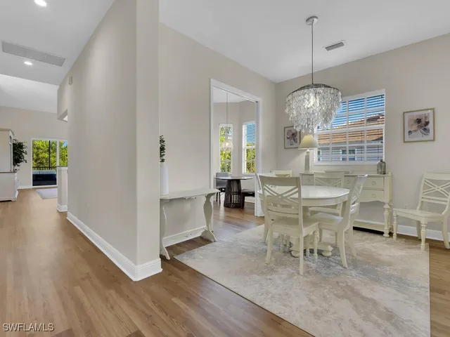 a dining room with wooden floor a chandelier a wooden table and chairs