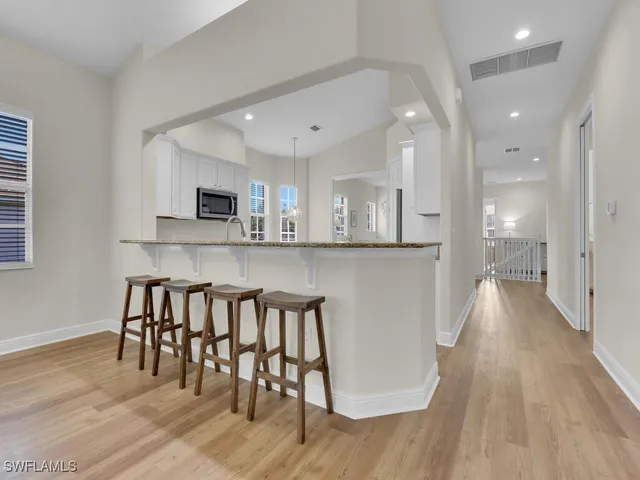 a kitchen with stainless steel appliances granite countertop a stove top oven a sink a dining table and chairs with wooden floor