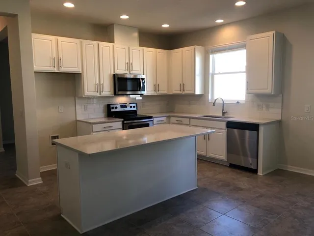 a kitchen with stainless steel appliances a sink a stove a microwave a refrigerator and cabinets